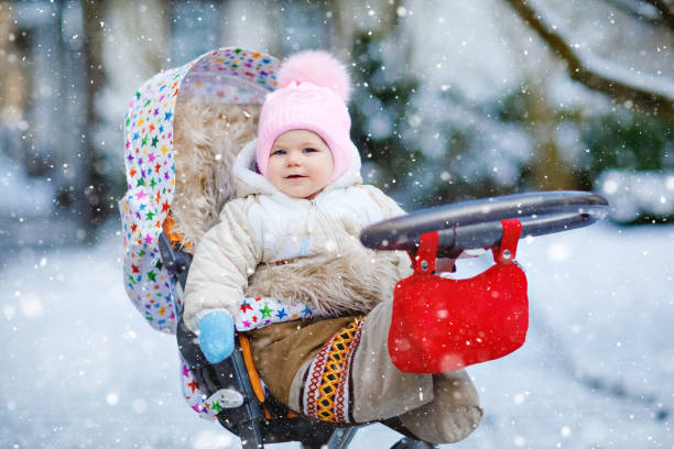 Cute little beautiful baby girl sitting in the pram or stroller on cold snowy winter day. Happy smiling child in warm clothes, fashion stylish baby coat. Baby's first snow. Cute little beautiful baby girl sitting in the pram or stroller on cold snowy winter day. Happy smiling child in warm clothes, fashion stylish baby coat. Baby's first snow baby stroller winter stock pictures, royalty-free photos & images