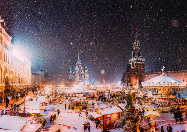 moskau, russland neujahr.  basilius-kathedrale im hintergrund.  weihnachtsfeiertage, verschneite winternachtslandschaft. weihnachtsmarkt auf festlich geschmücktem roten platz im schnee. - moskau stock-fotos und bilder