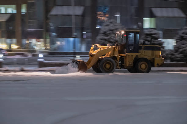 istock Wheel loader is removing snow at night during snowfall. Selective focus, blurred. Snow removing concept. 1286511406