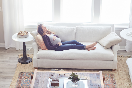 Full length shot of an attractive young pregnant woman relaxing on the sofa at home