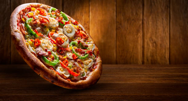istock Pizza with red pepper, green pepper, eggs an pepperoni. Side view on wood background, close up. Traditional Brazilian Pizza. 1286515603
