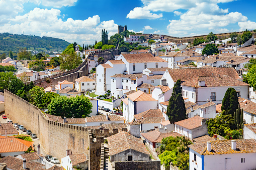 Portugal, Oeste region -  \n The old town Obidos, surrounded by a fortress wall and towers, view from above. Blue sky with fluffy clouds is on the background.