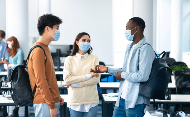 international students wearing medical masks and talking - lecture hall university talking student imagens e fotografias de stock