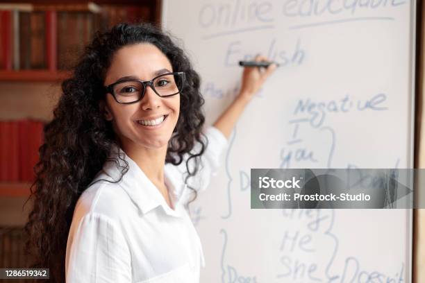 English Teacher Standing At Board Explaining Lesson To Students Stock Photo - Download Image Now