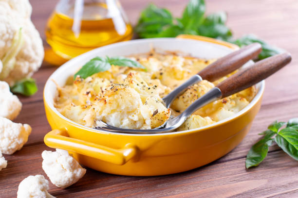 Cauliflower and cheese gratin in the baking dish on wooden table Cauliflower and cheese gratin in the baking dish on wooden table close-up casserole stock pictures, royalty-free photos & images