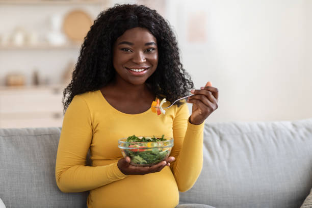 istock Smiling african expecting woman eating vegetable salad 1286520145