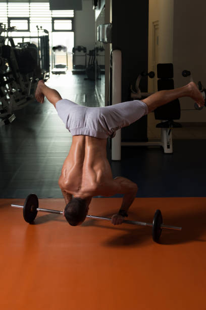 istock Athlete Exercising Handstand Push-Ups On Barbell In Gym 1286520524
