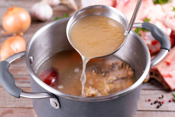 Saucepan with bouillon with a ladle. Bone broth Saucepan with bouillon with a ladle on the table. Bone broth Broth stock pictures, royalty-free photos & images