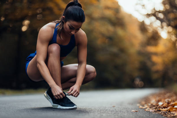 istock Sporty woman tying her shoelaces before run 1286522888