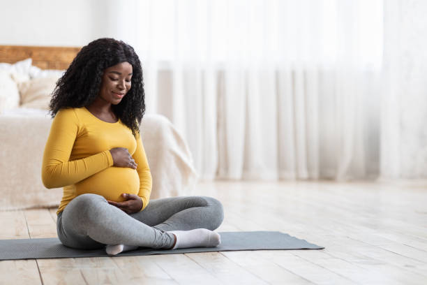 schwangere afrikanische frau, die zu hause sport macht - human pregnancy exercising relaxation exercise sport stock-fotos und bilder