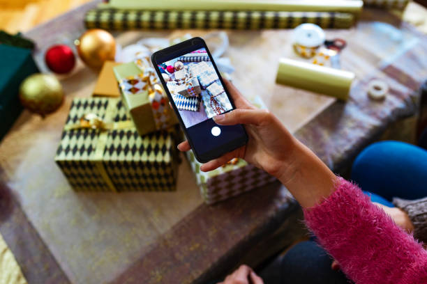 Hand photographing Christmas gift box stack with smart phone