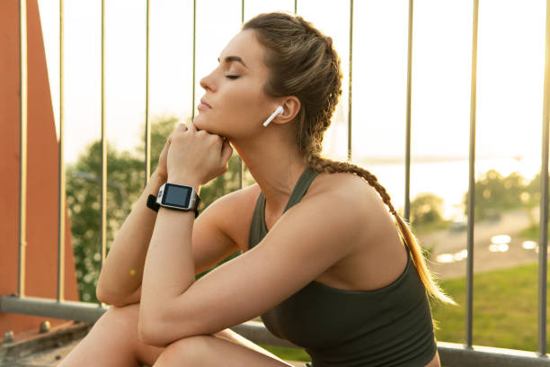 Sportive woman after fitness or jogging workout on a city street Beautiful sportive woman after fitness or jogging workout on a city street in ear headphones stock pictures, royalty-free photos & images