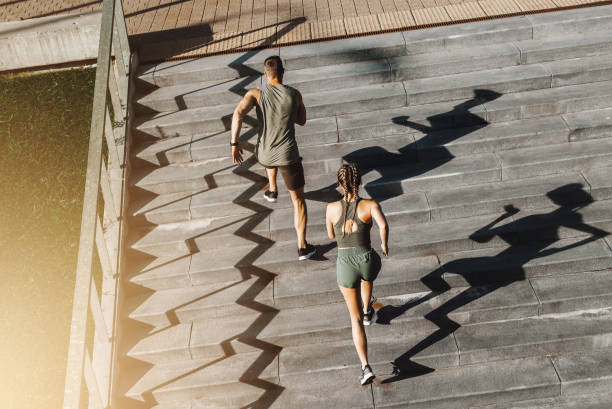 sportive couple are running upstairs in a city - upstairs imagens e fotografias de stock