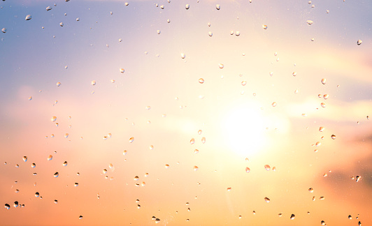 Close-up of raindrops on a window, drying in evening sunlight.