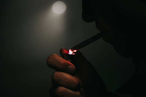 istock Lighting up a cigarette in backlit foggy street 1286532169