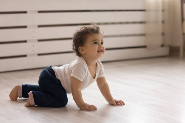 Small biracial baby infant crawl at home Cute small african American toddler baby child crawl on warm wooden home floor. Smiling little biracial infant kid play in children room indoors, explore world. Childcare, upbringing concept. crawling photos stock pictures, royalty-free photos & images