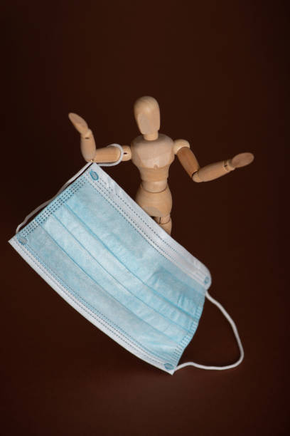 istock Wooden mannequin holding medical protective face mask 1286534302