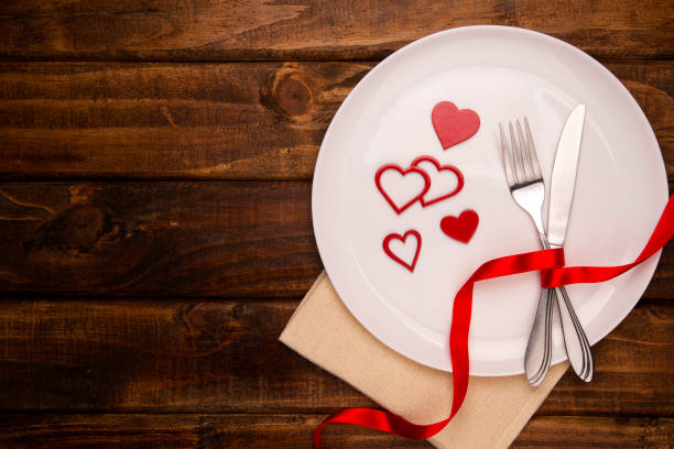 istock Festive table setting for Valentine's Day with fork, knife and hearts on a white wooden table. Space for text. Top view 1286540176