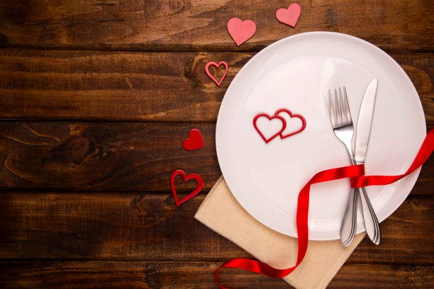 istock Festive table setting for Valentine's Day with fork, knife and hearts on a white wooden table. Space for text. Top view 1286540240