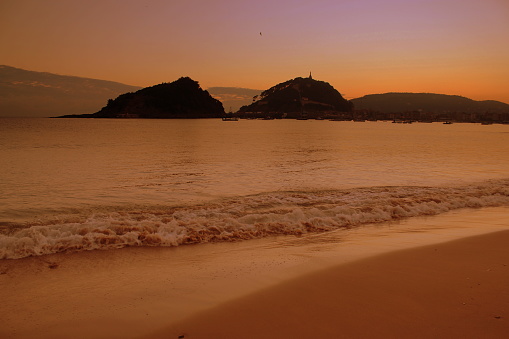 Every dawn in San Sebstián is different. The sky color is different and the water as well. The water covers the sand of the beach. We are enjoying La Concha bay in Donosti San Sebastián, located in the Basque Country, north of spain
