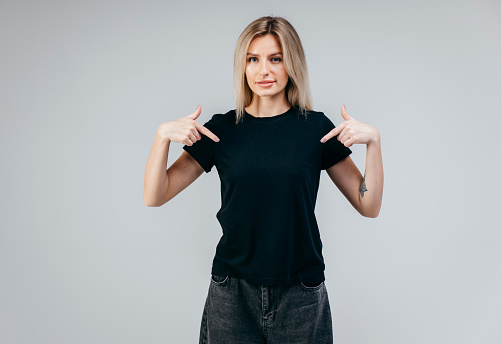 Stylish blonde girl wearing black t-shirt posing in studio