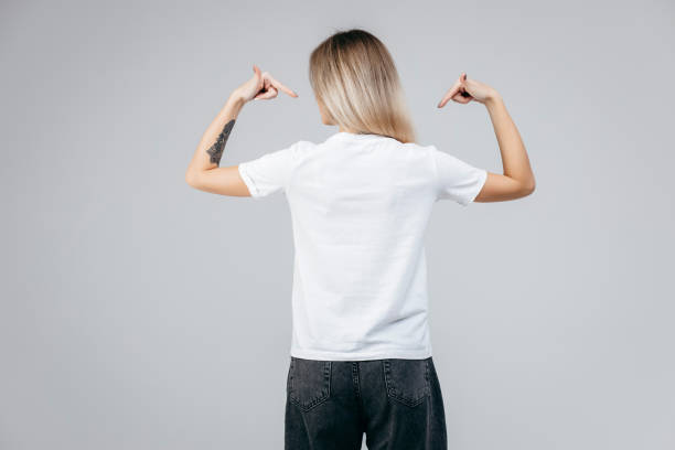 Back of stylish blonde girl wearing white t-shirt posing in studio Back of stylish blonde girl wearing white t-shirt posing in studio t shirt caucasian photography color image stock pictures, royalty-free photos & images