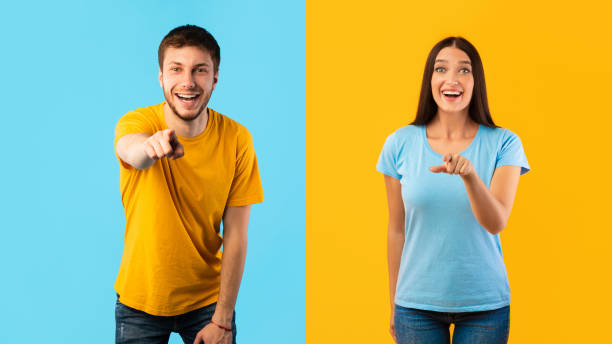 happy couple pointing finger at camera at studio - pointing women cheerful front view imagens e fotografias de stock