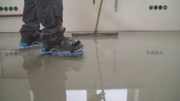 istock A worker rolls out the liquid floor with a trowel. Squeegee for distributing the mixture. The worker levels the liquid floor. Finishing works - Needle roller for bulk floor 1286542839