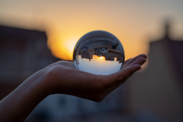 istock Woman hand holding a crystal ball with sunset background. 1286543561