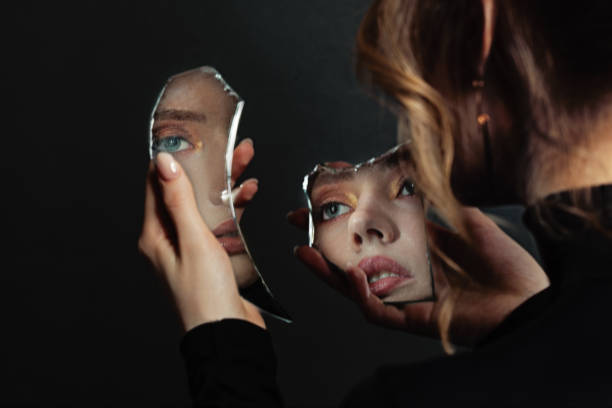 istock Perfect woman looking at broken self-image mirror on black background 1286544487