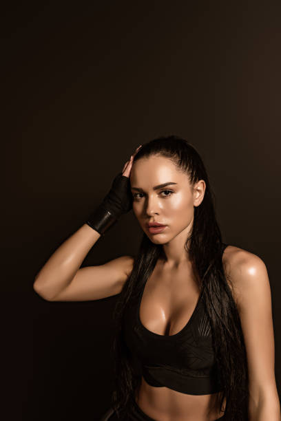 istock Beautiful sportswoman looking at camera and touching head isolated on black 1286545152