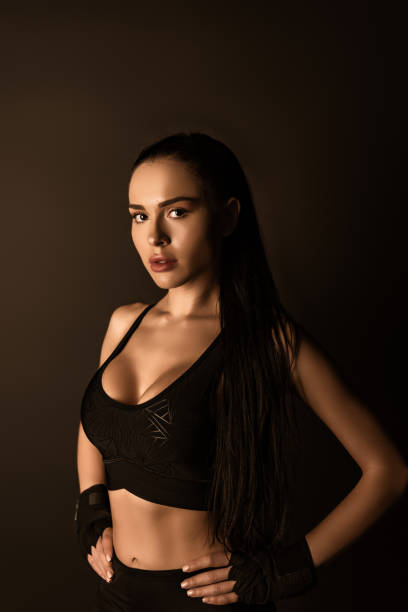 istock Beautiful sportswoman with hands on hips looking at camera isolated on black 1286545169