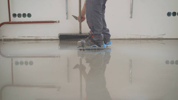 istock Finishing works - Needle roller for bulk floor. A worker rolls out the liquid floor with a trowel. Squeegee for distributing the mixture. The worker levels the liquid floor. 1286545345