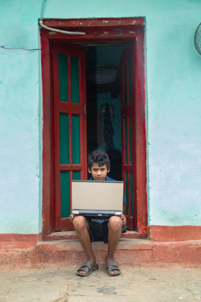 istock Indian village boy operating laptop computer system seating at home corridor 1286548079