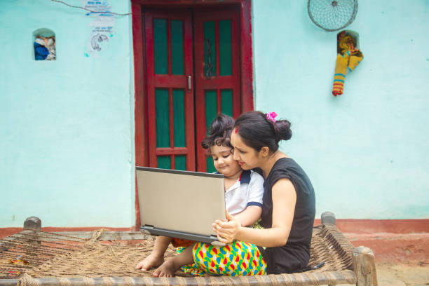 istock Indian rural mother teaching daughter online on laptop using internet. 1286548117