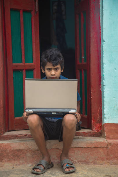 istock Indian village boy operating laptop computer system seating at home corridor 1286548303
