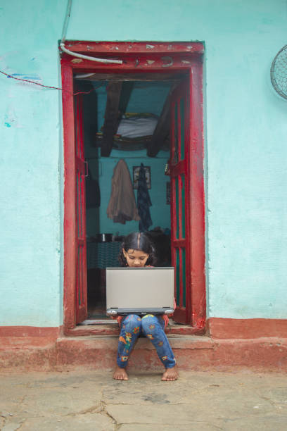 istock Indian village girl operating laptop computer system seating at home corridor 1286548880