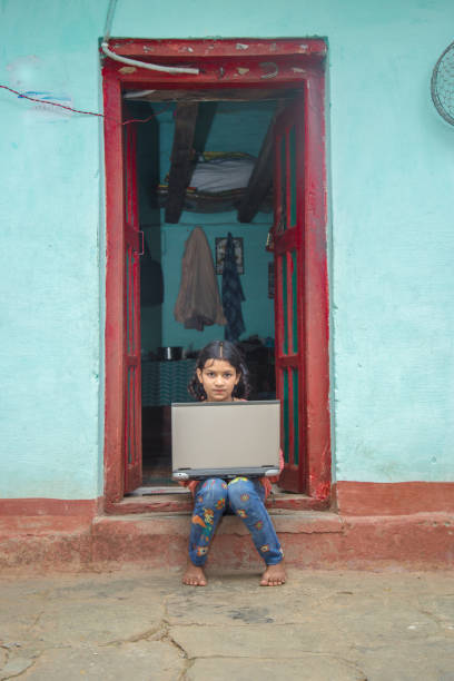 istock Indian village girl operating laptop computer system seating at home corridor 1286548926