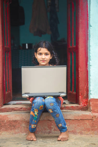 istock Indian village girl operating laptop computer system seating at home corridor 1286548952