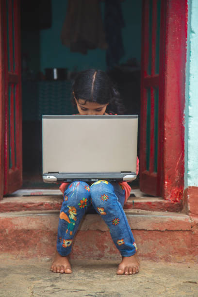 istock Indian village girl operating laptop computer system seating at home corridor 1286548995