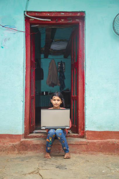 istock Indian village girl operating laptop computer system seating at home corridor 1286549043