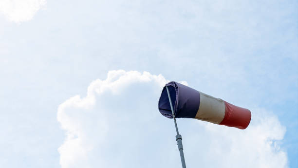 paleta de viento voladora con líneas rojas, blancas y azules sobre un fondo de cielo dramático. pruebe la dirección del viento, los instrumentos de velocidad del viento. espacio para el texto. - windsock sky natural phenomenon gale fotografías e imágenes de stock