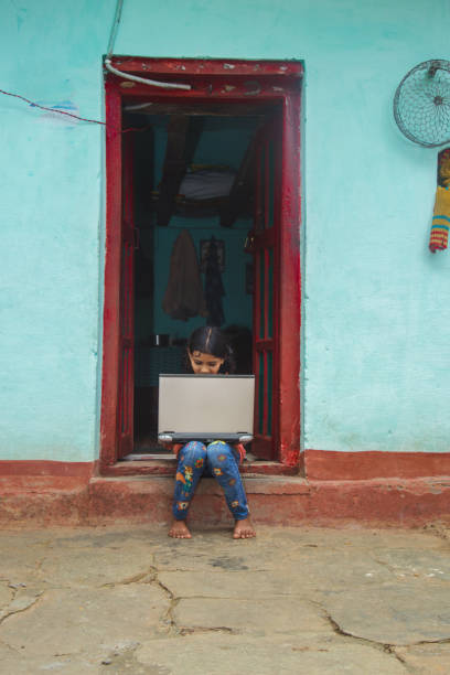 istock Indian village girl operating laptop computer system seating at home corridor 1286549157