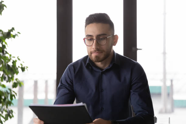 istock Focused young arabic ethnicity male manager looking at paper document. 1286549444