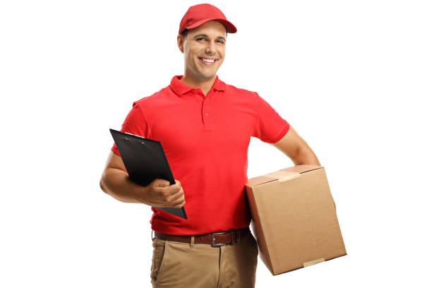 istock Male courier in a uniform holding a cardboard box and a clipboard 1286550846