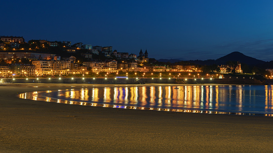 Long exposure photography of San Sebastian cityscape. Calmness. Peaceful  water of Bay of Biscay. fashionable touristic resort. Concepts of the beauty in nature. Still life in golden colors.