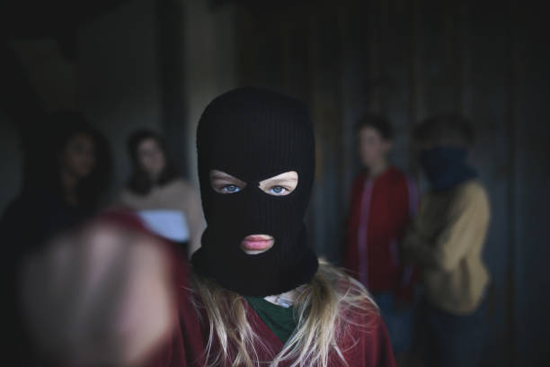 fille avec le masque du gang d’adolescents restant à l’intérieur dans le bâtiment abandonné, attaquant avec le poing. - youth culture gang member adolescence family photos et images de collection