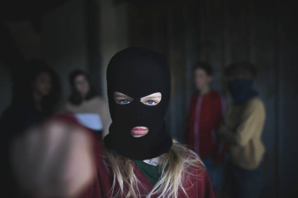 放棄された建物の屋内に立って、拳で攻撃するティーンエイジャーギャングからのマスクを持つ女の子。 - youth culture gang member adolescence family ストックフォトと画像