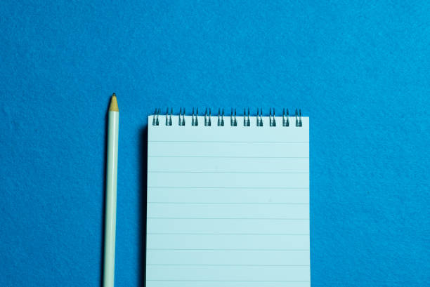 istock blank page of notebook and pencil on light blue background 1286559017