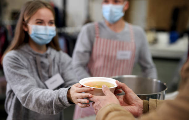 Volunteers serving hot soup for homeless in community charity donation center, coronavirus concept. Volunteers serving hot soup for ill and homeless in community charity donation center, food bank and coronavirus concept. serving size photos stock pictures, royalty-free photos & images